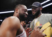Miami Heat guard Dwyane Wade, left, chats with LeBron James before the Heat's NBA basketball game against the Brooklyn Nets, Wednesday, April 10, 2019, in New York. Wade is retiring after the game. (AP Photo/Kathy Willens)