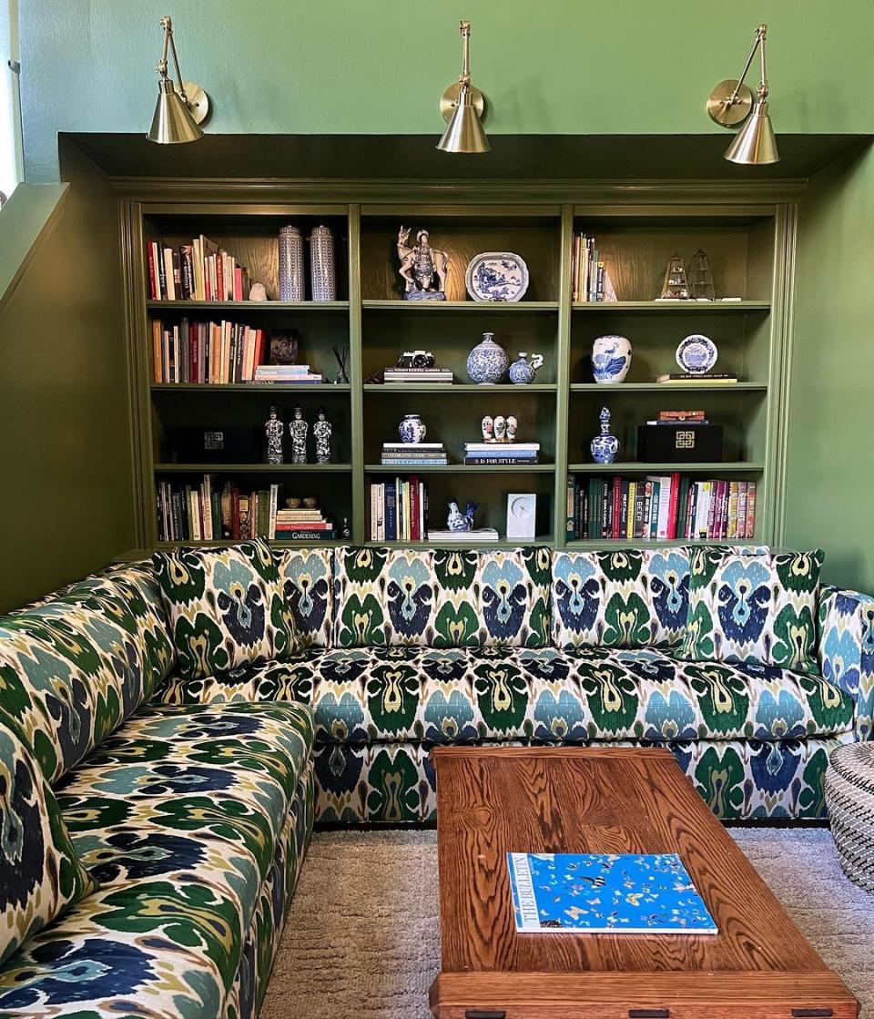 a green wall with books and a coffee table