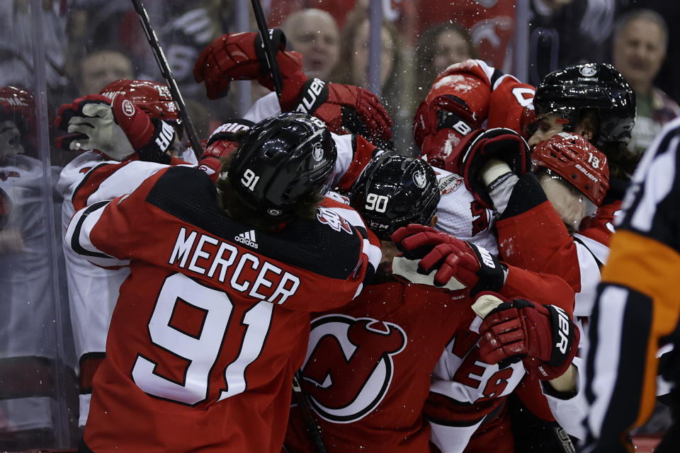 New Jersey Devils center Dawson Mercer (91) and Tomas Tatar (90) fight with Carolina Hurricanes right wing Jesse Puljujarvi (13) during the first period of an NHL hockey game, Sunday, March 12, 2023, in Newark, N.J. (AP Photo/Adam Hunger)