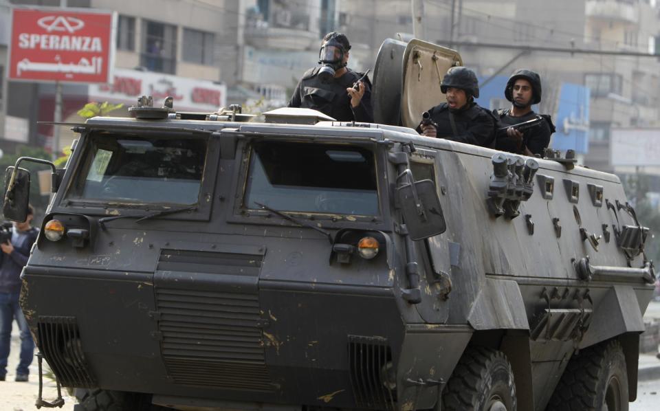 Riot police look from armoured personnel vehicle during clashes with supporters of Muslim Brotherhood and ousted President Mursi at Nasr City district in Cairo