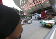 Medi Bastoni looks at mirror as he walks backwards in Bekasi, outskirt of Jakarta, Indonesia, Thursday, Aug, 22, 2019. The Indonesian man is walking over 700-kilometer (430-mile) backward from his home in eastern Java to the country's capital to draw awareness of deforestation.(AP Photo/Achmad Ibrahim)