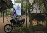 An Indian villager walks past a banner featuring U.S. Vice President-elect Kamala Harris with a message wishing her best, in Thulasendrapuram, the hometown of Harris' maternal grandfather, south of Chennai, Tamil Nadu state, India, Wednesday, Jan. 20, 2021. A tiny village in a remote part of South India is gearing up for celebrations ahead of Kamala Harris' inauguration as the first female vice president of the United States. (AP Photo/Aijaz Rahi)