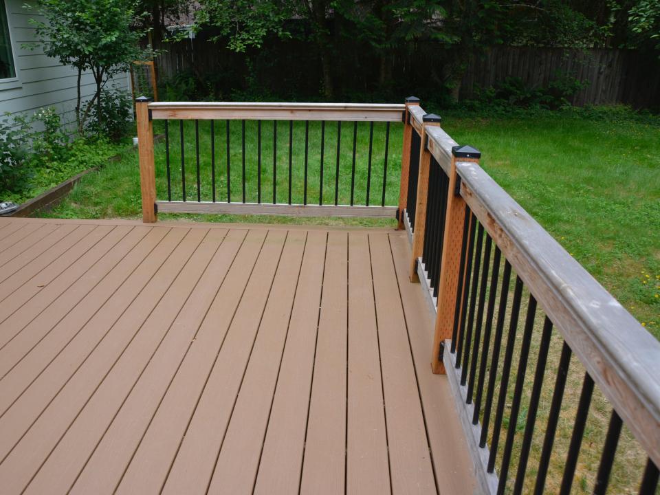 empty wood deck corner with wood railing and black metal beams