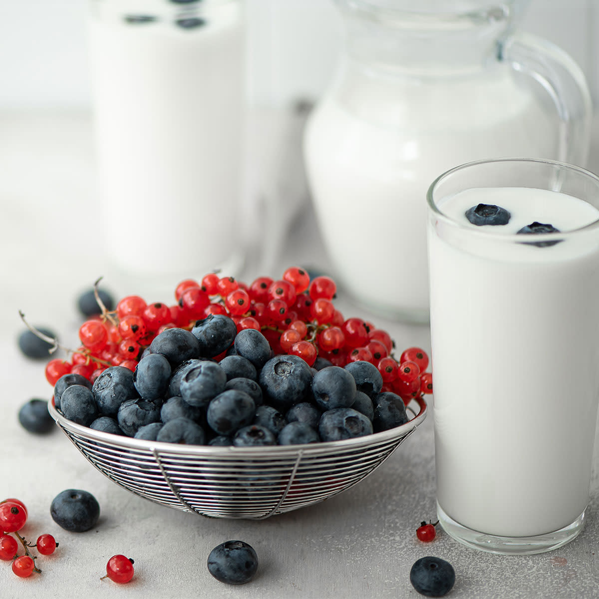 bowl of berries beside glasses of kefir