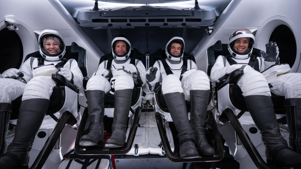     The four astronauts of SpaceX's private mission Polaris Dawn pose in black and white spacesuits in their Dragon capsule. 