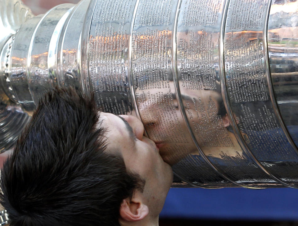 FILE - Boston Bruins' Patrice Bergeron is reflected as he kisses the Stanley Cup at Tia's Restaurant in Boston on Thursday, June 16, 2011, one day after the Bruins beat the Vancouver Canucks 4-0 in Game 7 of the NHL hockey Stanley Cup Finals. Bruins forward Patrice Bergeron has retired. The five-time Selke Trophy winner announced Tuesday, July 25, 2023, that he will not return for a 20th season with the only team he has ever played for. The Bruins captain said he is leaving with no regrets. (AP Photo/Elise Amendola, File)