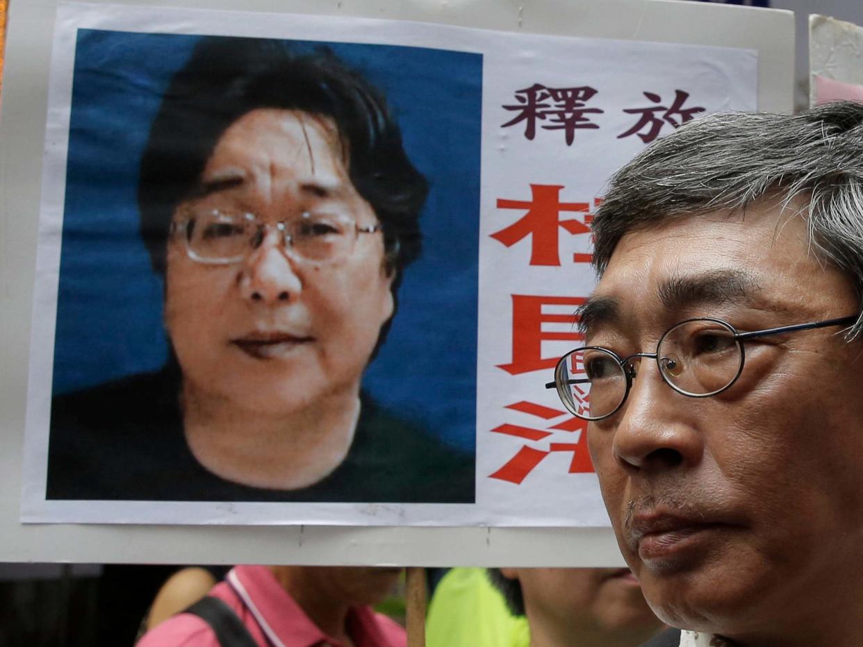 A picture of missing bookseller Gui Minhai is shown on a placard beside freed Hong Kong bookseller Lam Wing-kee, as the protesters are marching to the Chinese central government's liaison office in Hong Kong: AP