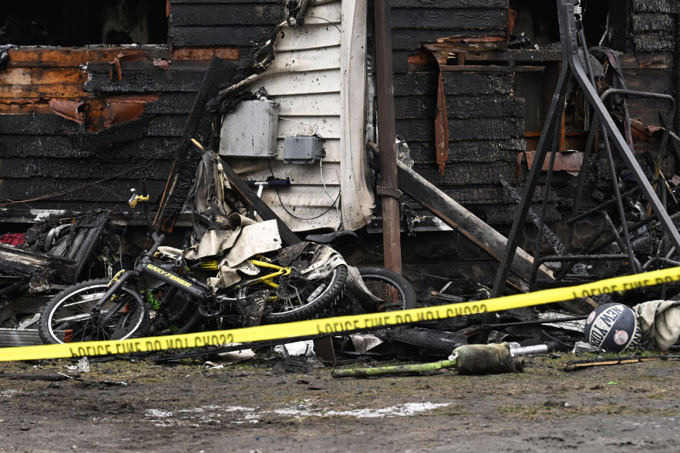 Charred siding and children's toys are strewn about at a two-family home Wednesday, Jan. 3, 2024, in Somers, Conn., in the aftermath of a fatal fire. Four children died Tuesday night in a fire that broke out in the two-family home. The children, ages 5, 6, 8 and 12, were found inside the house where 11 people lived, fire and town officials said. (AP Photo/Jessica Hill)