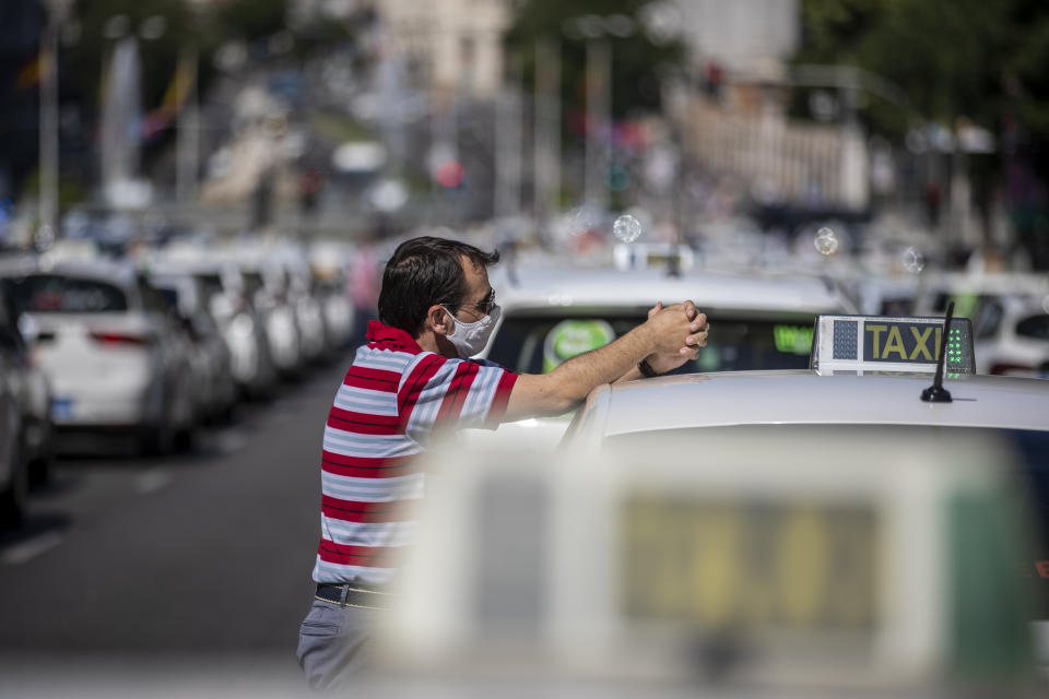 A taxi driver wearing a face mask to prevent the spread of coronavirus stands during a taxi drivers protest in downtown Madrid, Spain, Tuesday, June 30, 2020. Taxi drivers are demanding assistance due to lack of clients and private hire. (AP Photo/Manu Fernandez)