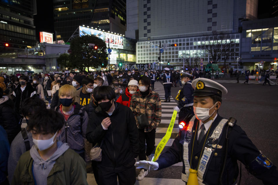 Police direct visitors around Shibuya crossing, a popular location for New Year's Eve gathering Friday, Jan. 1, 2021, in Tokyo. Tokyo's downtown Shibuya district has canceled its annual countdown event at a popular "scramble Intersection" area outside of its main train station, and a "countdown vision" screen will be turned off at 11 p.m. (AP Photo/Kiichiro Sato)