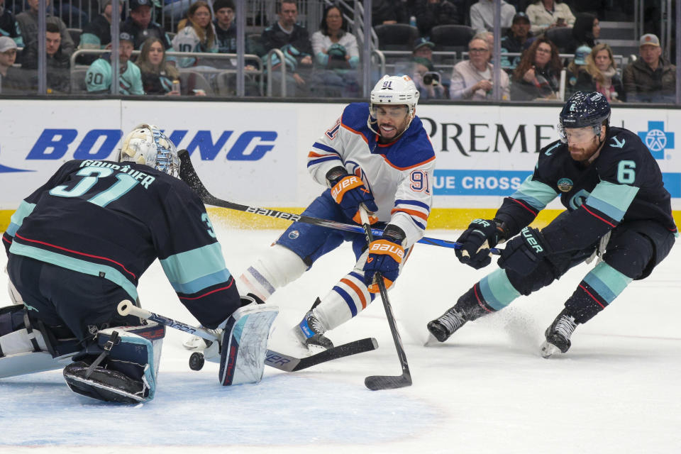 Edmonton Oilers left wing Evander Kane (91) shoots the puck as Seattle Kraken goaltender Philipp Grubauer (31) and Adam Larsson defend during the second period of an NHL hockey game Saturday, March 2, 2024, in Seattle. (AP Photo/Jason Redmond)