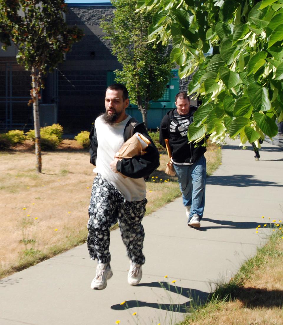 Inmates sprint for freedom Wednesday, May 30, 2012, after being released from the jail in Grants Pass, Ore., due to layoffs of guards forced by the failure of a tax increase. The Josephine County Sheriff’s Office released 39 inmates, dropping the population at the jail to 60 _ half of them federal prisoners held on contract. About half will finish their sentences on work crews, while the rest were waiting for trial. The most common charges were for drug crimes, minor assaults, burglary, identity theft and probation violations. (AP Photo/Jeff Barnard)