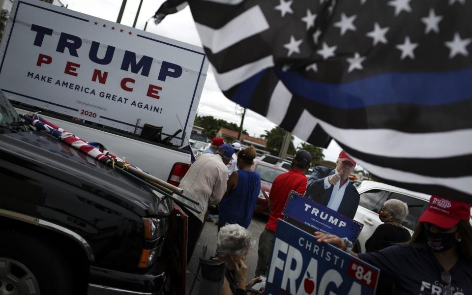  President Donald Trump hold signs during a rally outside an early voting polling location - Bloomberg