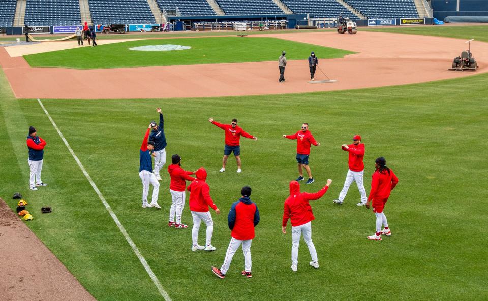 WooSox players begin to warm up as the grounds crew works on the first day of practice at Polar Park Tuesday.