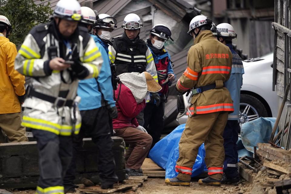 A person looks at a body of a family member found from a collapsed house caused by powerful earthquake in Suzu, Ishikawa Prefecture Wednesday, Jan. 3, 2024. A series of powerful earthquakes hit western Japan, damaging buildings, vehicles and boats, with officials warning people in some areas on Tuesday to stay away from their homes because of a risk of more strong quakes. (AP Photo/Hiro Komae)