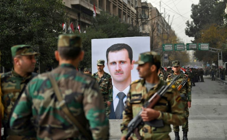 Syrian soldiers walk past a portrait of President Bashar al-Assad during a celebration last month marking a year since the retaking of the second city of Aleppo after a suffocating siege