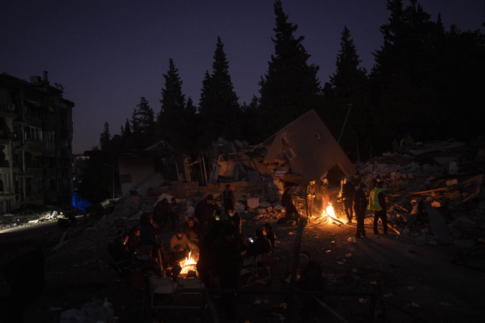 Friends and relatives of the Daghli family gather around bonfires while rescue teams, not pictured, search for family members under the rubble of a destroyed building in Antakya, southeastern Turkey, Wednesday, Feb. 15, 2023. The earthquakes that killed more than 39,000 people in southern Turkey and northern Syria is producing more grieving and suffering along with extraordinary rescues and appeals for aid. (AP Photo/Bernat Armangue)