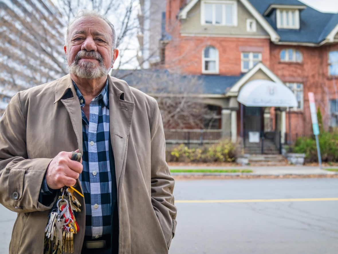 Ottawa resident Issa Khoury, who came to Canada nearly 50 years ago, said he has been entrusted by the Syrian government with checking in on Syria's shuttered embassy building on Cartier Street. Here he holds up the sizeable mass of keys he holds for the property.  (Michel Aspirot/Radio-Canada - image credit)