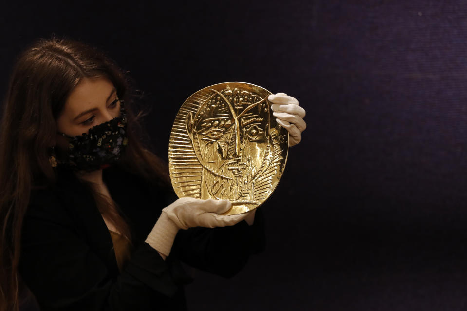 <p>A Bonhams employee holds the Visage de Faune, a 22-carat gold repousse plate, which has an estimate of £250,000-350,000 (349,000-489,000. USD) at Bonhams Picassomania sale in London, Thursday, March 18, 2021. Bringing together works by the master himself, as well as photographs and ephemera, Bonhams' new sale, Picassomania on 23 March in London, will celebrate his expansive oeuvre – as well as all things Picasso. (AP Photo/Frank Augstein)</p>
