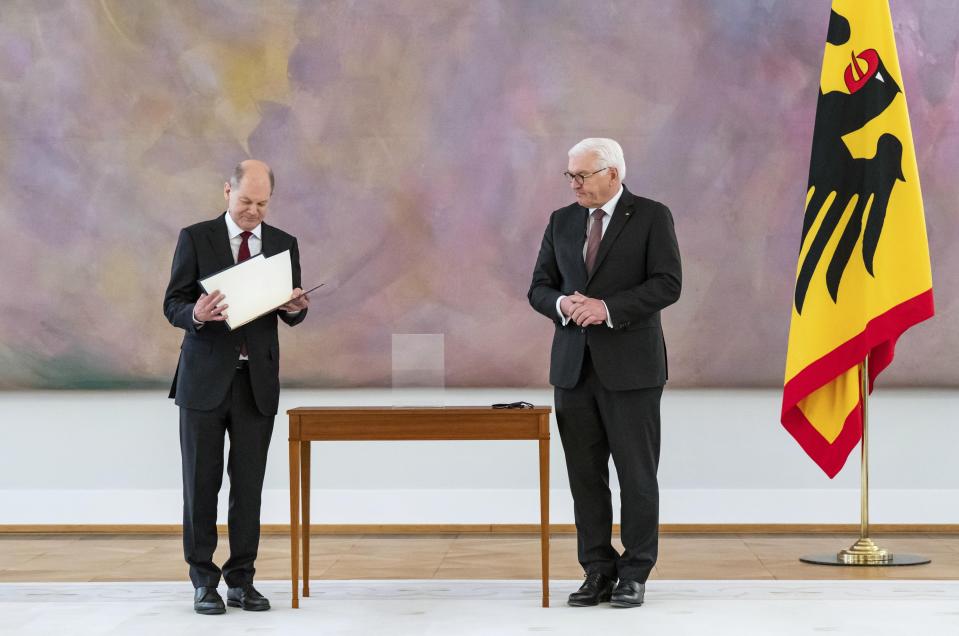 New elected German Chancellor Olaf Scholz, left, holds his letter of appointment presented by German President Frank-Walter Steinmeier, right, during a reception at Bellevue Palace in Berlin, Germany, Wednesday, Dec. 8, 2021. Scholz has become Germany's ninth post-World War II chancellor, opening a new era for the European Union’s most populous nation and largest economy after Angela Merkel’s 16-year tenure. Scholz’s government takes office with high hopes of modernizing. (Bernd Von Jutrczenka/dpa via AP)