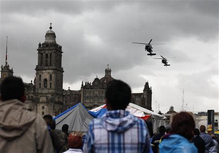 Protesters look at helicopters of the federal police as they fly over the Zocalo in Mexico City September 13, 2013. (REUTERS/Tomas Bravo)