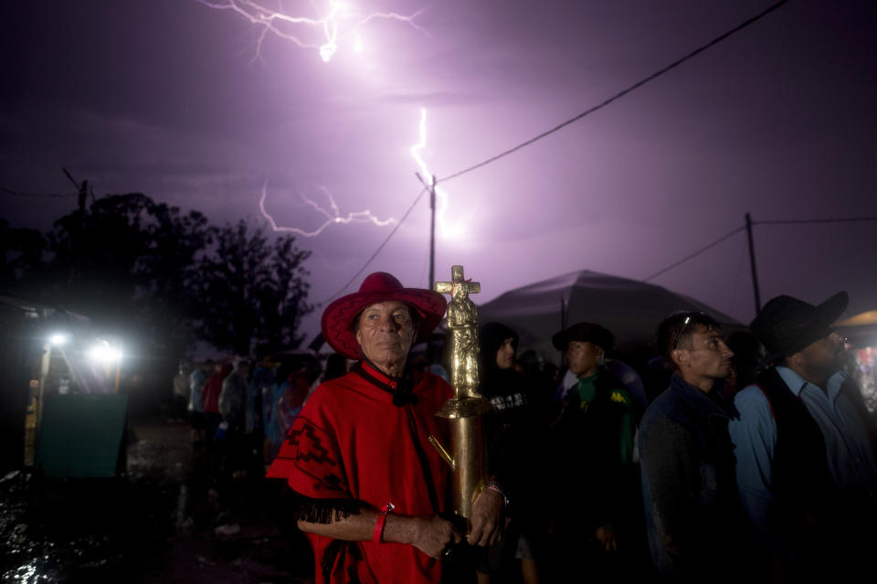 Cloaked in red, Julio Rivero holds a figure of Saint Gauchito Gil while visiting his sanctuary, in Mercedes, Argentina, Sunday, Jan. 7, 2024. Worshiped by many faithful Argentines, the folk saint depicts a traditional cowboy known as the gaucho, a long-haired man with a mustache, red handkerchief around his neck and belt. He is revered as a sort of Robin Hood figure, joining the army and deserting in favor of stealing and distributing wealth amongst the country's poor. He was later captured and hung from a tree on Jan. 8, 1878. (AP Photo/Mario De Fina)