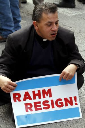 A Catholic priest, one of the protesters, sits down on Chicago's Michigan Avenue during a protest march against police violence in Chicago, Illinois December 24, 2015. REUTERS/Frank Polich