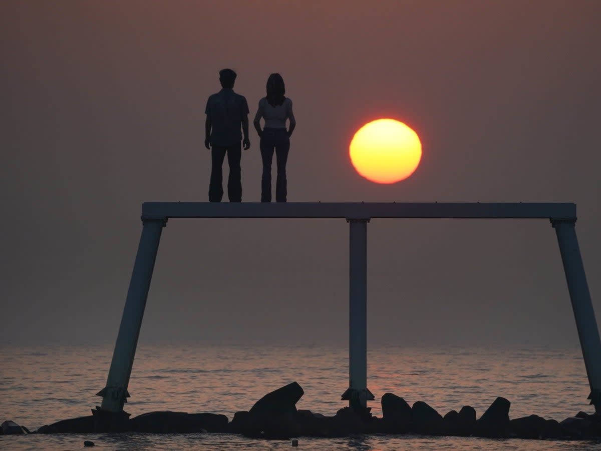 13 February 2023: The sunrises through the sea mist over the sculpture “The Couple” by Sean Henry at Newbiggin-by-the-Sea on the Northumberland coast. (PA)