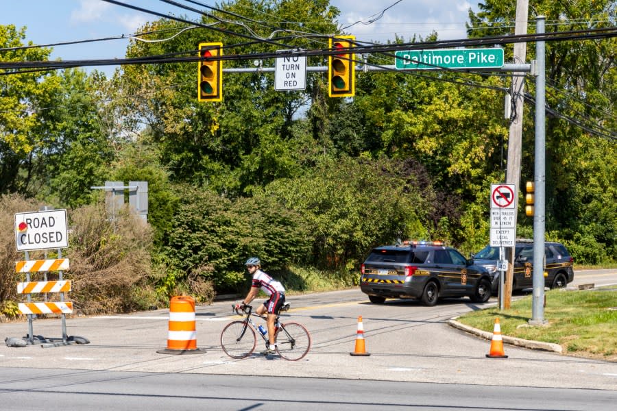 A biker passes by Pennsylvania State Police Officers blocking off a road as the search continues for the escaped murderer Danelo Cavalcante in Chadds Ford, Pa., on Wednesday, Sept., 6, 2023. Cavalcante was able to escape a prison yard in suburban Pennsylvania last week by climbing up a wall and over razor wire, officials said at a news conference Wednesday. (Tyger Williams/The Philadelphia Inquirer via AP)