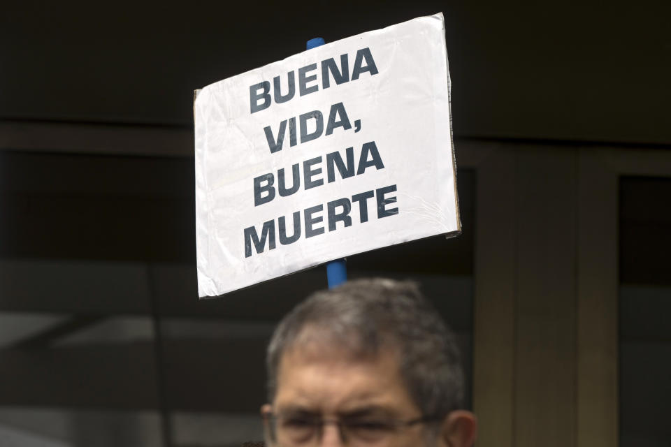 A man stands during a protest outside one of the main courts in Madrid, Spain, Friday, April 5, 2019. A Madrid court has released Angel Hernandez, a 70-year-old man who admitted to helping his 61-year-old wife end her life and who was diagnosed 30 years ago with multiple sclerosis and had for years asked him to help her die. The case has reignited a national debate in Spain about assisted suicide. Banner reads 'Good life, good death'. (AP Photo/Paul White)