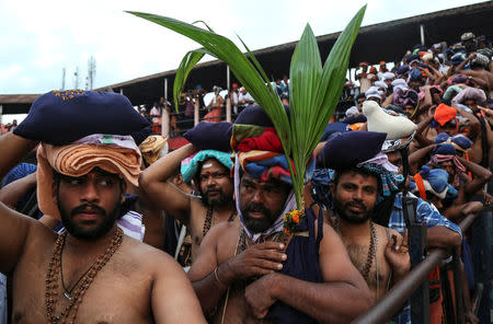 A Hindu devotee holds a coconut plant as he waits with others in queues inside the premises of the Sabarimala temple in Pathanamthitta district in Kerala, India, October 18, 2018. REUTERS/Sivaram V