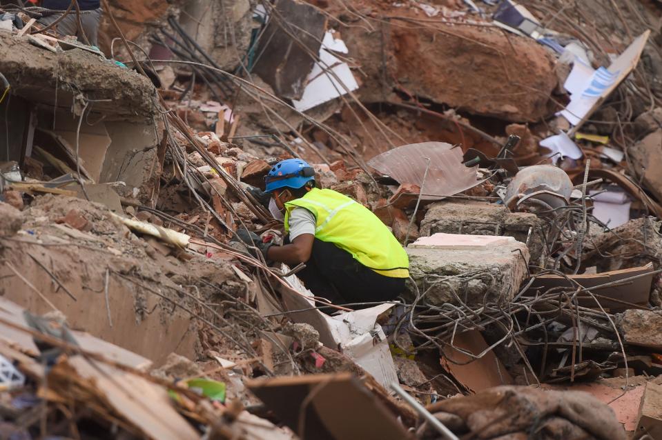 A rescue worker searches for people in the rubble of a collapsed five-storey apartment building in Mahad. (Photo by PUNIT PARANJPE/AFP via Getty Images)