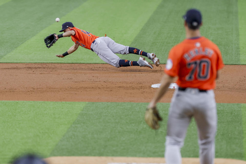 Houston Astros second baseman Mauricio Dubón, left, deflects a ground ball hit by Texas Rangers' Wyatt Langford (not shown) during the first inning of baseball game, Monday, April 8, 2024, in Arlington, Texas. (AP Photo/Gareth Patterson)