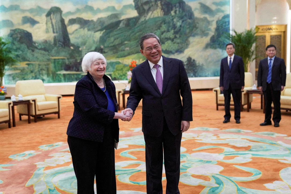 Janet Yellen shaking hands with Li Qiang in a room with ornate flooring and a mural on the wall behind them.