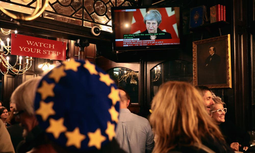 An anti-Brexit campaigner watches a live broadcast of the prime minister, Theresa May, delivering a speech from No 10 after a day of high drama in Westminster