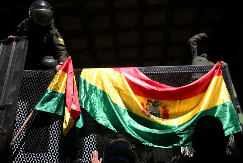 Police officers hang Bolivian flags at an entrance to the Police Operations Tactical Unit headquarters in La Paz