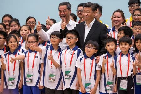 China's President Xi Jinping and Hong Kong's outgoing Chief Executive Leung Chun-ying give thumbs up as they pose for photographs with members of the Hong Kong Police Force's Junior Police Scheme during a visit at the scheme's Permanent Activity Center and Integrated Youth Camp in Hong Kong, China, June 30, 2017. REUTERS/Justin Chin/Pool