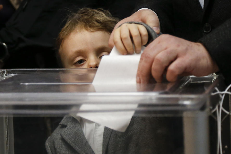 Ukrainian President Petro Poroshenko casts his ballot as his grandson Petro, looks at the ballot at a polling station, during the second round of presidential elections in Kiev, Ukraine, Sunday, April 21, 2019. Top issues in the election have been corruption, the economy and how to end the conflict with Russia-backed rebels in eastern Ukraine. (AP Photo/Efrem Lukatsky)