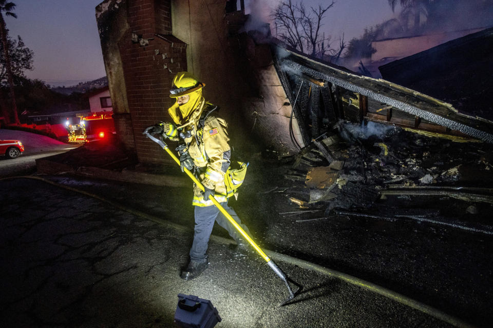 Firefighter Jesse Sparks mops up at a destroyed home as the Hillside Fire burns in San Bernardino, Calif., on Thursday, Oct. 31, 2019. Whipped by strong wind, the blaze destroyed multiple residences. (AP Photo/Noah Berger)