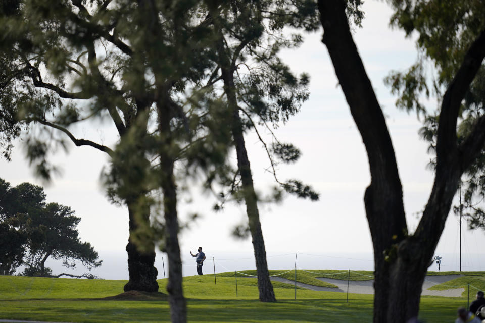A man records on his cell phone on an otherwise nearly empty South Course during the first round of the Farmers Insurance Open golf tournament at Torrey Pines on Thursday, Jan. 28, 2021, in San Diego. (AP Photo/Gregory Bull)