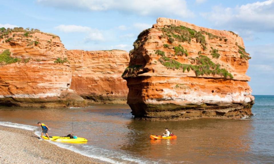 People landing kayaks by the sea stacks at Ladram Bay.