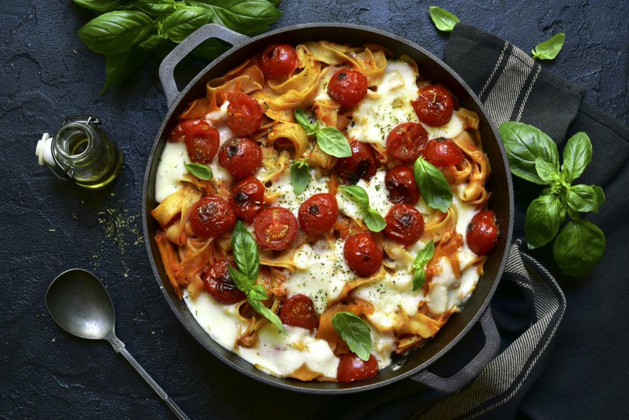 Casserole with tomatoes, mozzarella and basil pasta casserole in a cast iron pan
