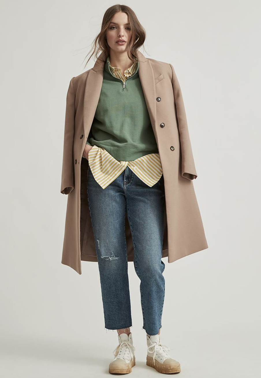 model wearing white sneakers, blue jeans, green sweater and beige Oversized Double-Breasted Coat (photo via RW&CO)