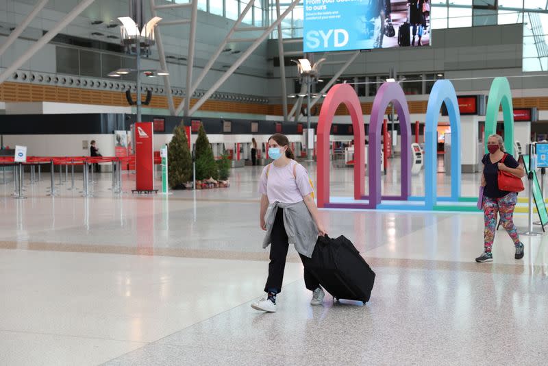 Gente usa mascarilla mientras camina por una terminal áerea para viajes locales mayormente vacía en el Aeropuerto de Sídney luego de un brote de COVID-19 en Sídney