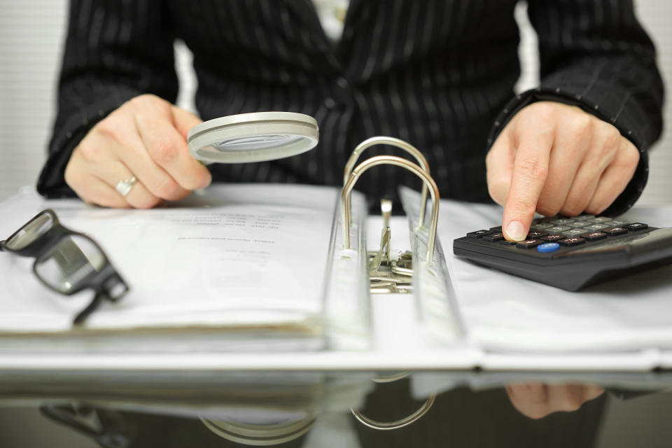 An accountant examining a ledger and using a calculator. 