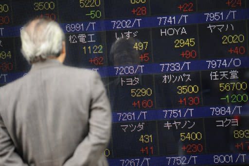 A man looks at an electronic shares index board in front of a securities company in Tokyo, 2008. Asian markets rallied and the euro held on to strong gains from New York after the European Central Bank chief said it would do "whatever it takes" to save the under-pressure single currency