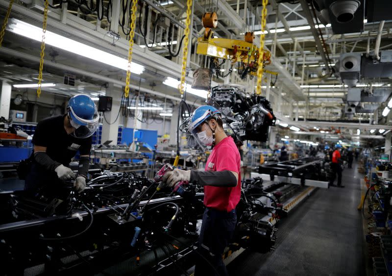 Employees wearing protective face masks and face guards work on the automobile assembly line during the outbreak of the coronavirus disease (COVID-19) at the factory of Mitsubishi Fuso Truck and Bus Corp. in Kawasaki