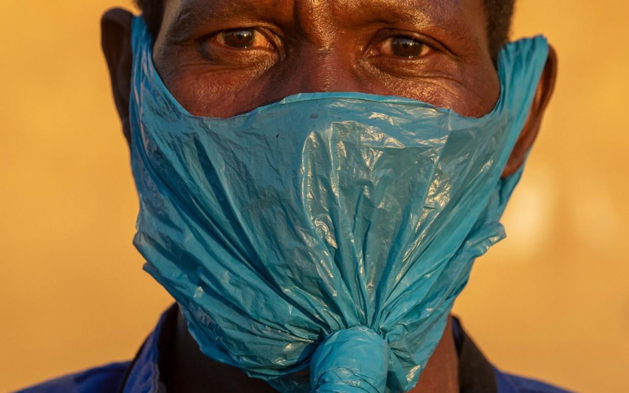 In this photo a man wears a plastic bag for a mask on his face as a precaution against the spread of the coronavirus, in Katlehong, Johannesburg - Themba Hadebe/AP