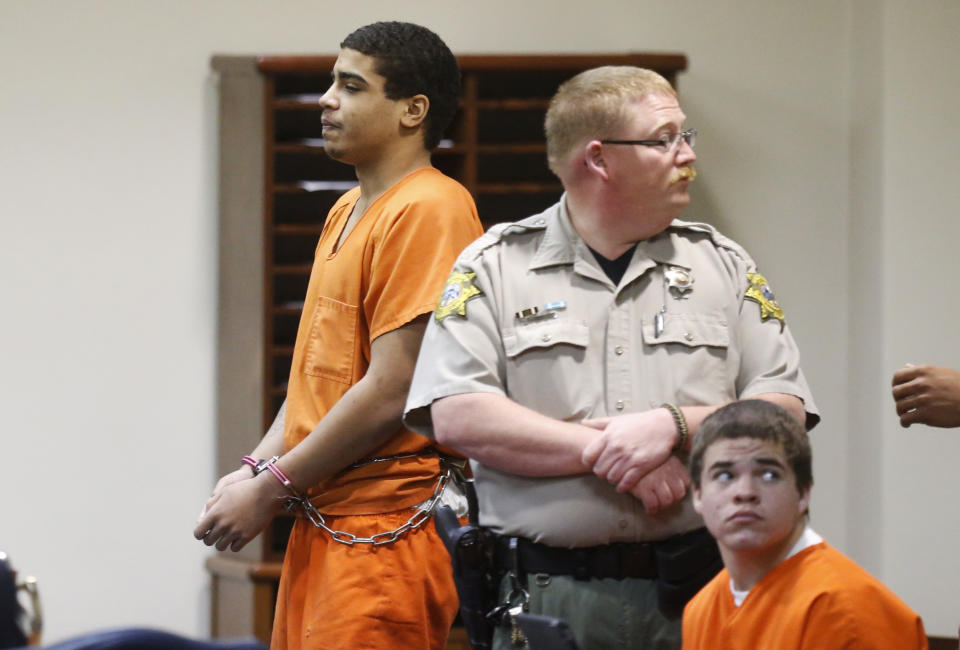 In this photo shot through a courtroom door, defendant Chancey Luna, left, is led from the courtroom following a hearing in Duncan, Okla., Wednesday, March 12, 2014. At right is defendant Michael Jones. Both are charged in the murder of Australian Christopher Lane. (AP Photo/Sue Ogrocki)