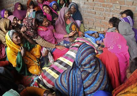 Family members mourn as they sit next to the body of their relative, who died after consuming locally brewed liquor, outside their residence at Malihabad town in Uttar Pradesh January 13, 2015. REUTERS/Pawan Kumar